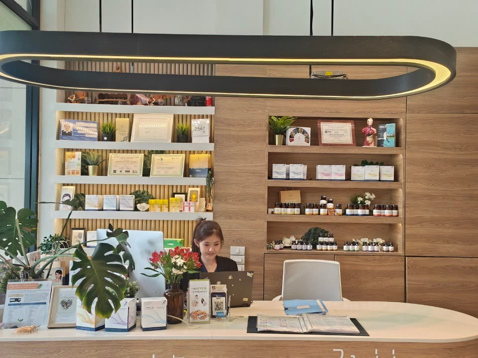 ชั้นวางผลิตภัณฑ์และประกาศนียบัตรด้านหลังเคาน์เตอร์ต้อนรับ Thrive Wellness Clinic