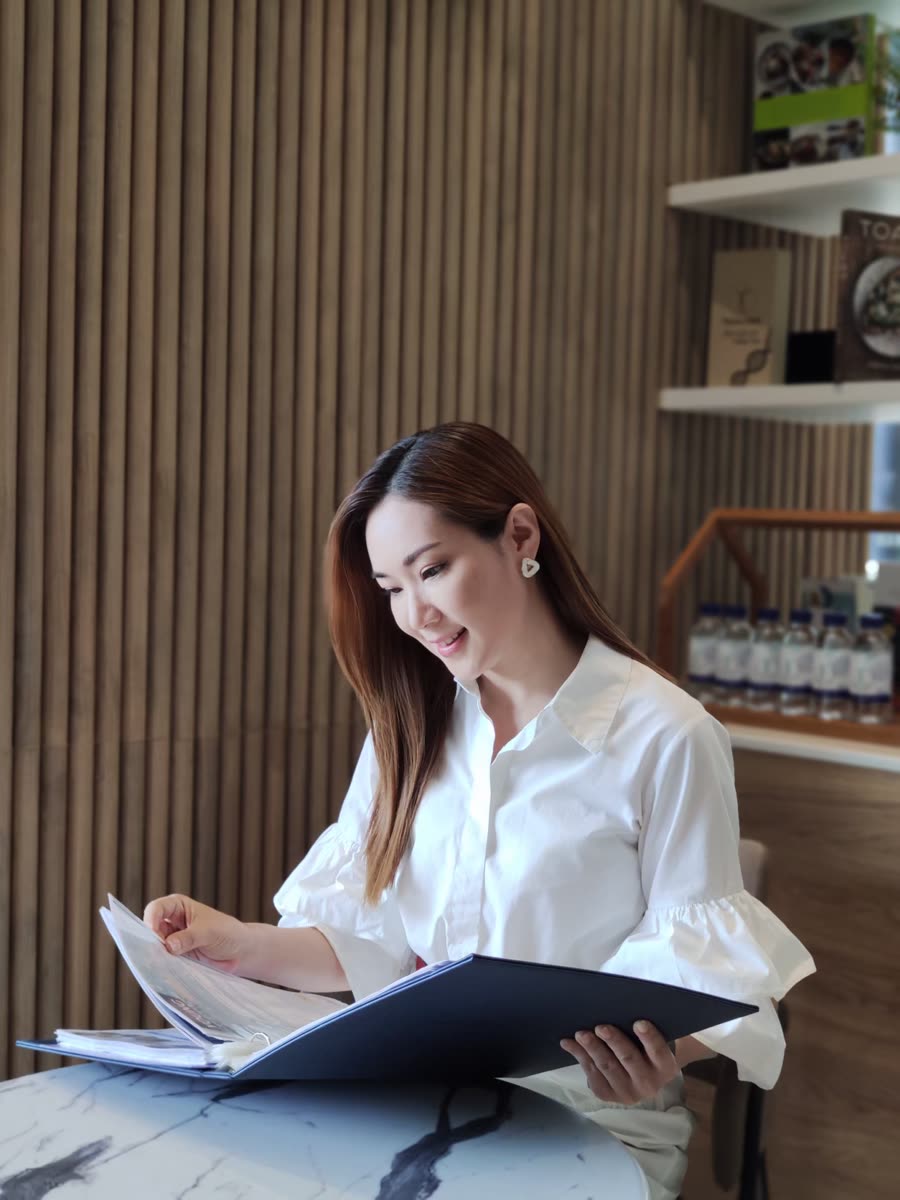 ผู้รับบริการนั่งอ่านเอกสารข้อมูลบริการที่โต๊ะหินอ่อนในมุมนั่งรอของคลินิก